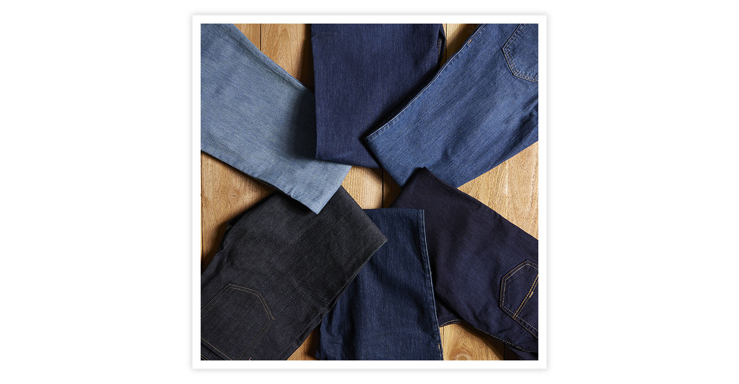 Justin Jeans of different wash colors laying on a wood table posed in a circle.